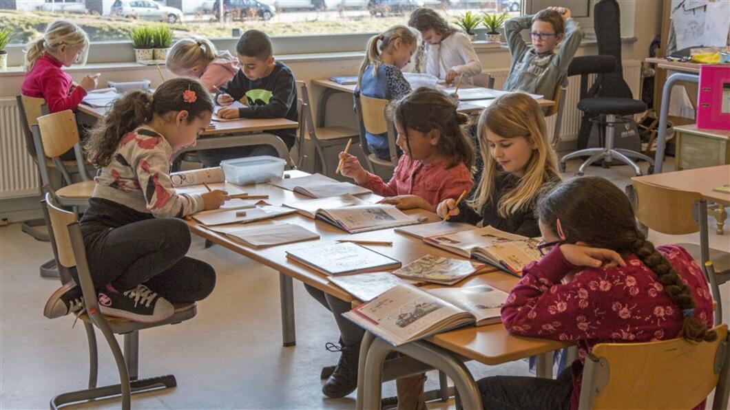 Kinderen zitten in een klaslokaal samen te werken.